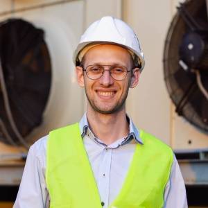 Portrait of smiling engineer in helmet making diag.jpg
